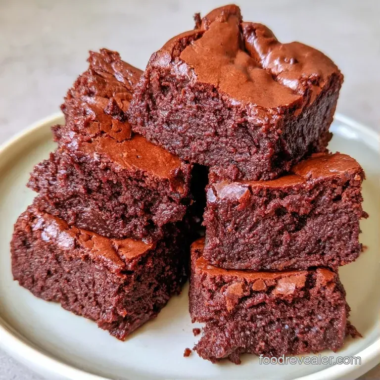 A neat square of dark chocolate cake dusted with cocoa powder and paired with a dollop of whipped cream and berries.